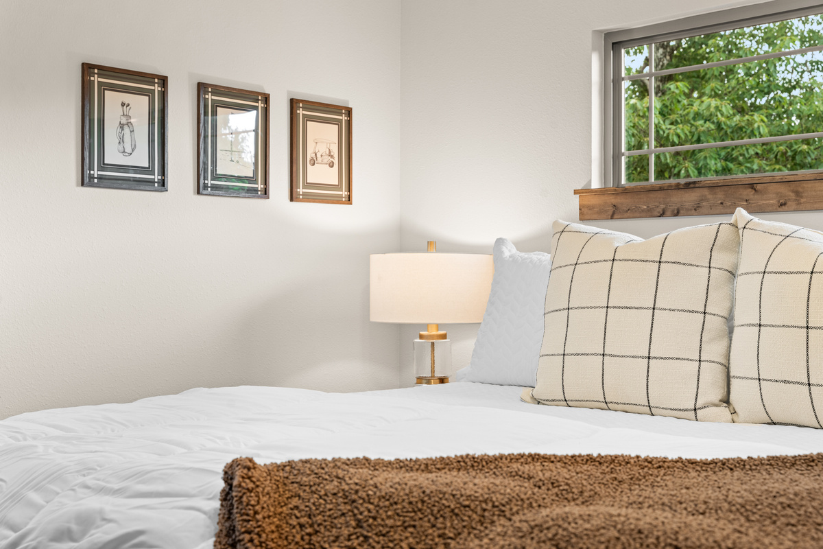 A golf-sketch trio, a gold lamp, and windowpane pillows dress the upstairs king.