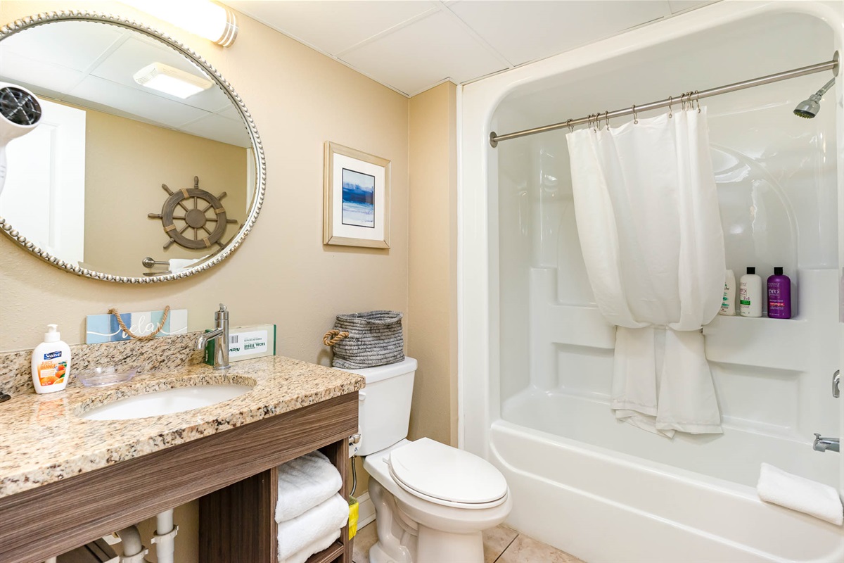 A well lit, sparkling clean bathroom with sets of fresh towels!