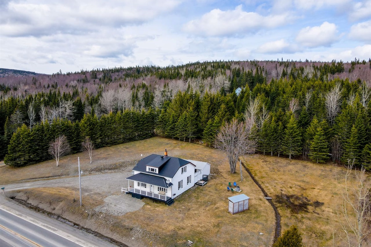 Vue aérienne du chalet, du foyer extérieur et son immense terrain boisé.