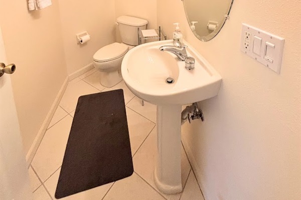 Convenient half bathroom with pedestal sink, tile flooring, and clean neutral finishes.