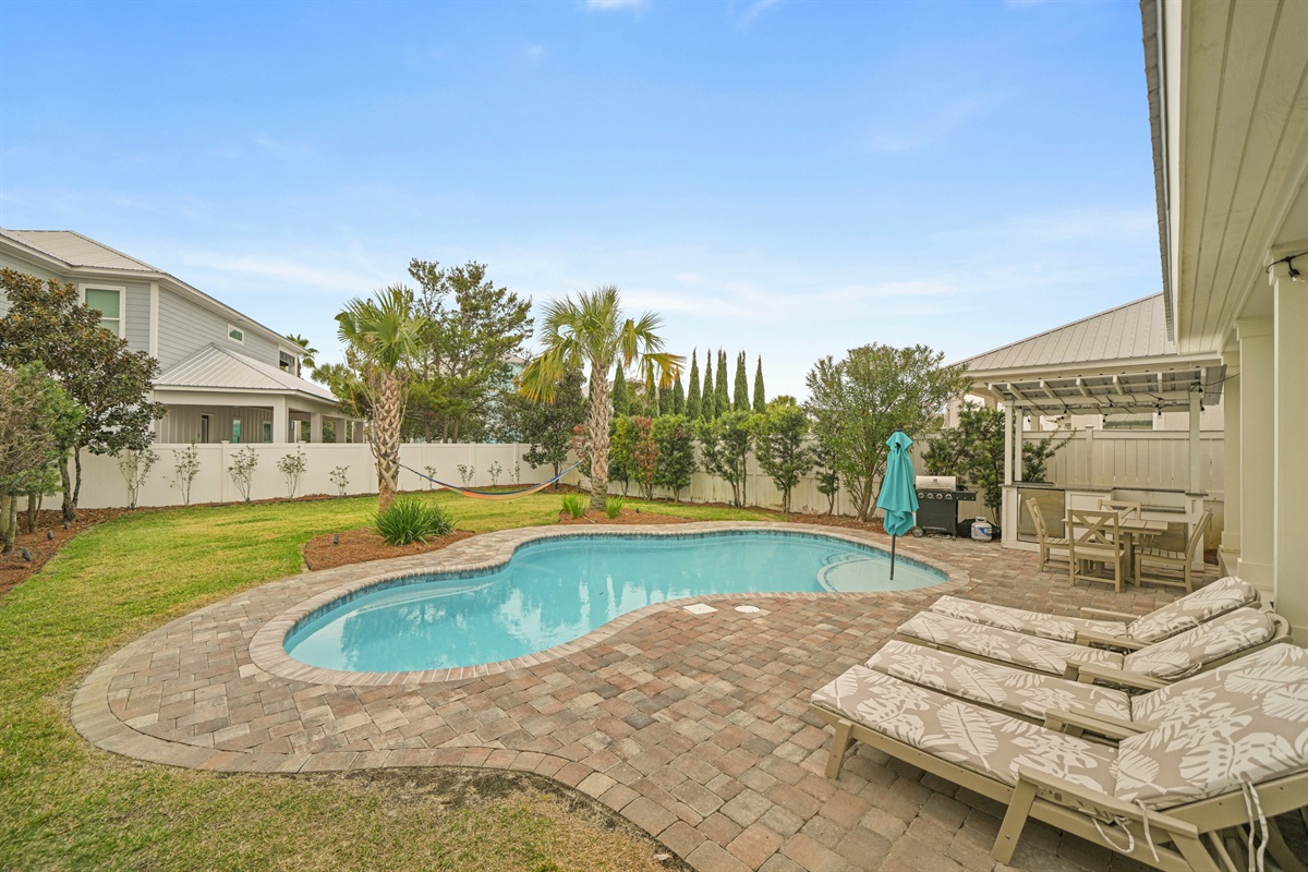 Daytime view of the private pool, patio, and landscaped backyard.