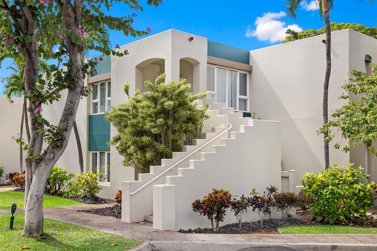 View of the building (a four-plex) from the parking lot. You have one step up onto the sidewalk, no further stairs into or within the condo. The staircase leads to an upstairs condo