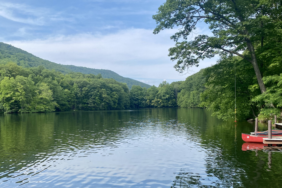 Community lake with dock and rowboats, framed by the Hudson Highlands