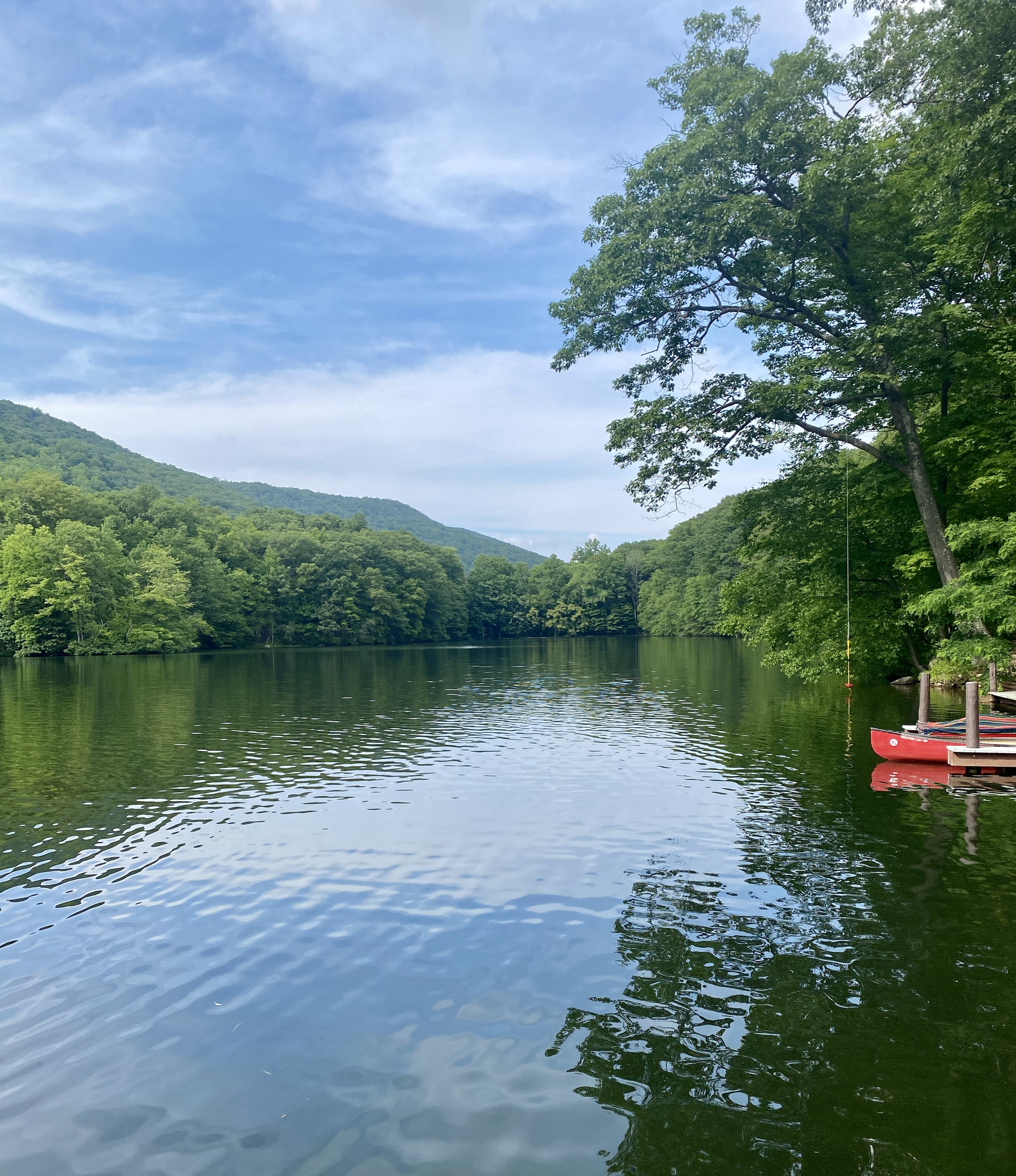 Community lake with dock and rowboats, framed by the Hudson Highlands
