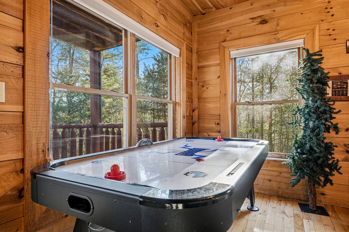 Challenge the family to an air hockey showdown surrounded by the treetops of the Great Smoky Mountains | This Gatlinburg-area cabin game room brings the fun indoors with forest views from every window