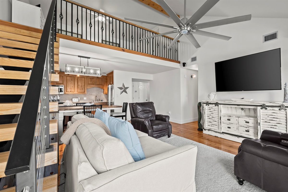 Unwind in the living room of our Cotton Bayou condo, featuring a comfortable couch and cozy recliners, perfect for relaxing after a day of coastal adventures. Enjoy modern decor, a smart TV, and a welcoming atmosphere.