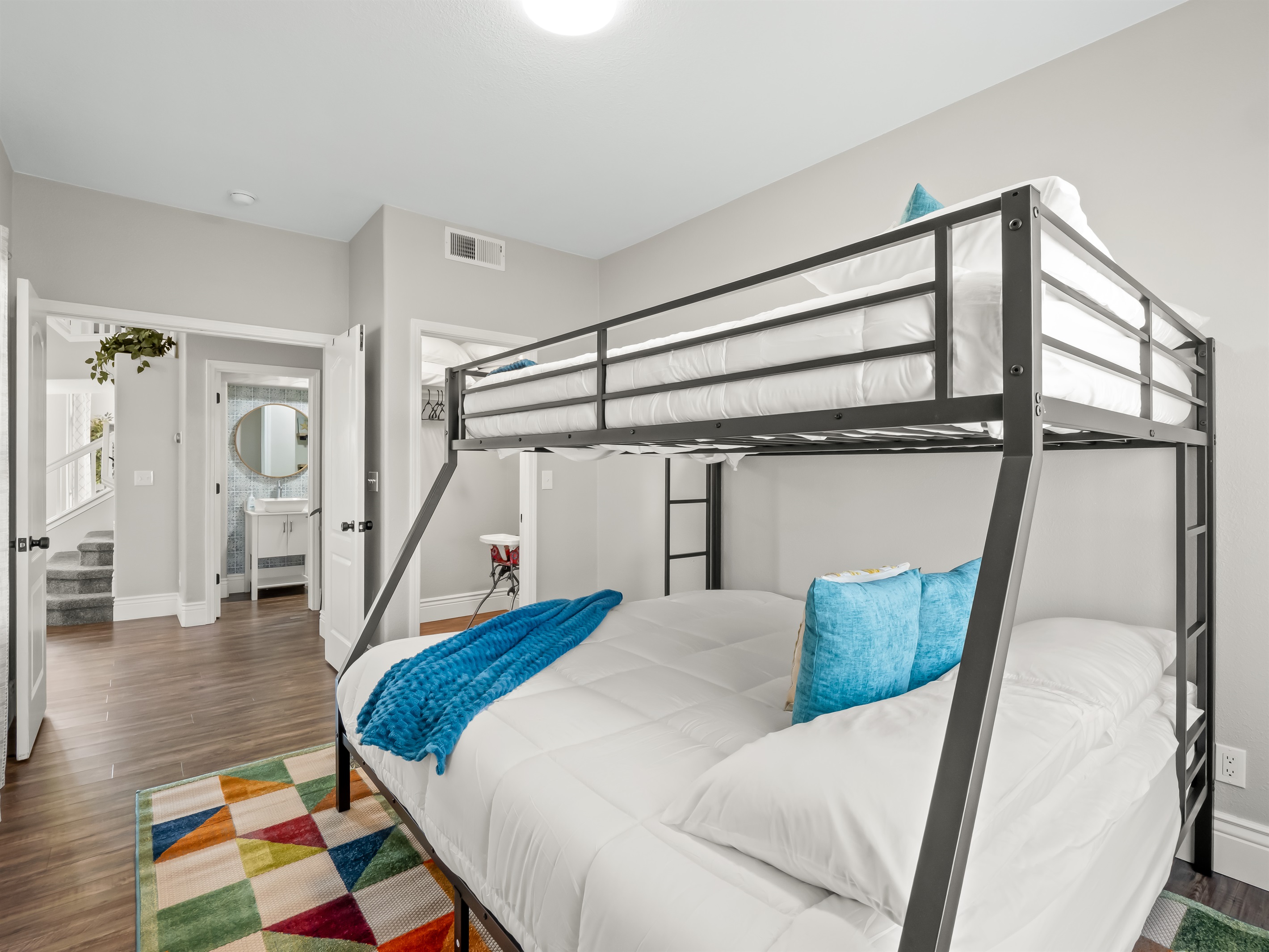 Spacious bunk room with a queen bed below and twin above, soft bedding, and easy access to the hallway bathroom—ideal for kids, teens, or additional guests.
