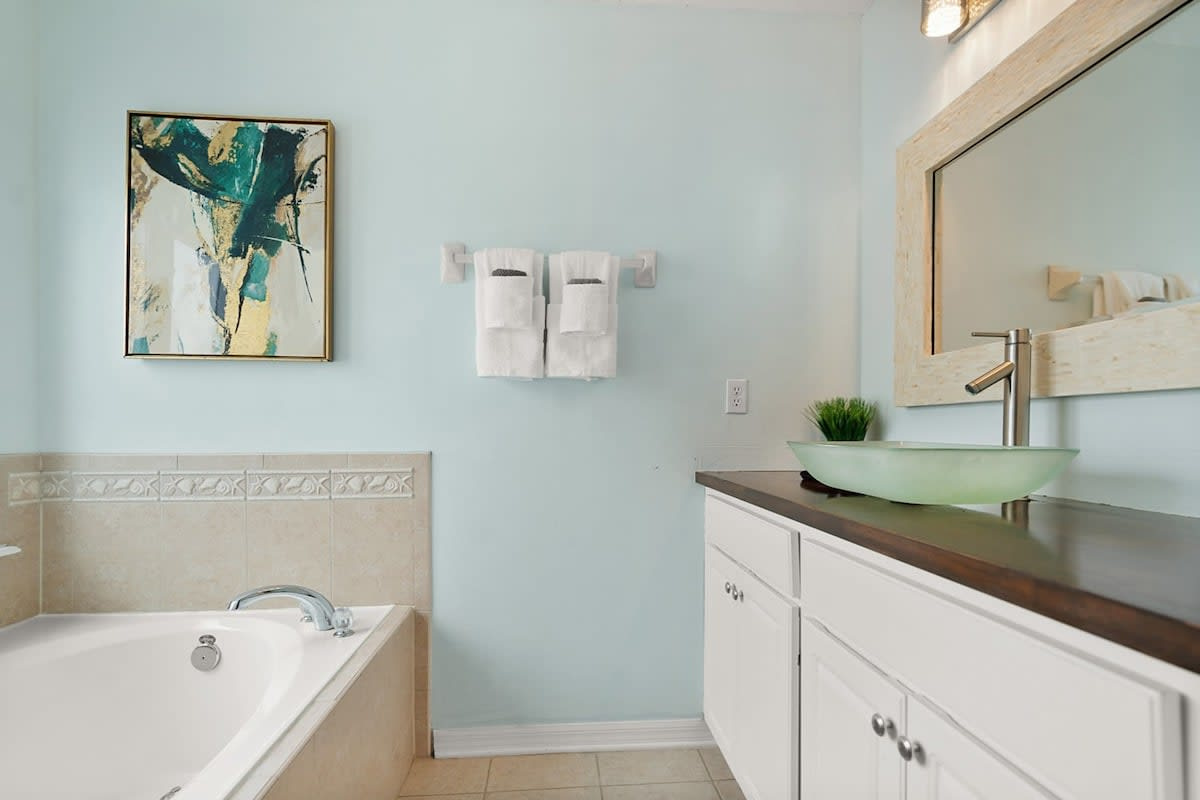 The second-floor primary bathroom, with a tub and the towels stacked and waiting. Two of the four bedrooms have their own en-suite, which makes a house of ten run considerably more smoothly first thing.