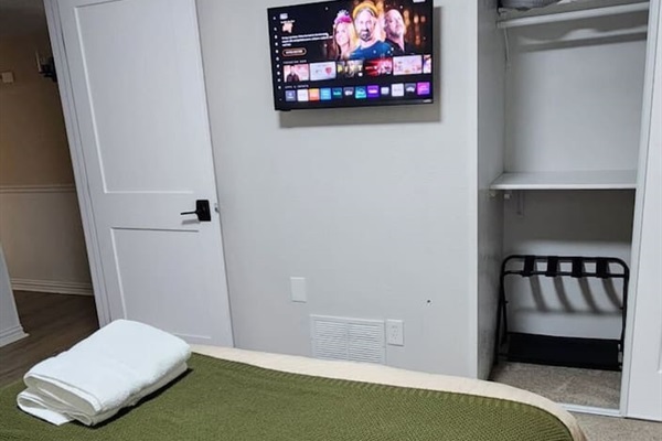 This bright queen bedroom offers a cozy retreat with a Smart TV with streaming services, blackout curtains, and a quiet ceiling fan for uninterrupted sleep. The queen bed is dressed with premium linens and supportive pillows.