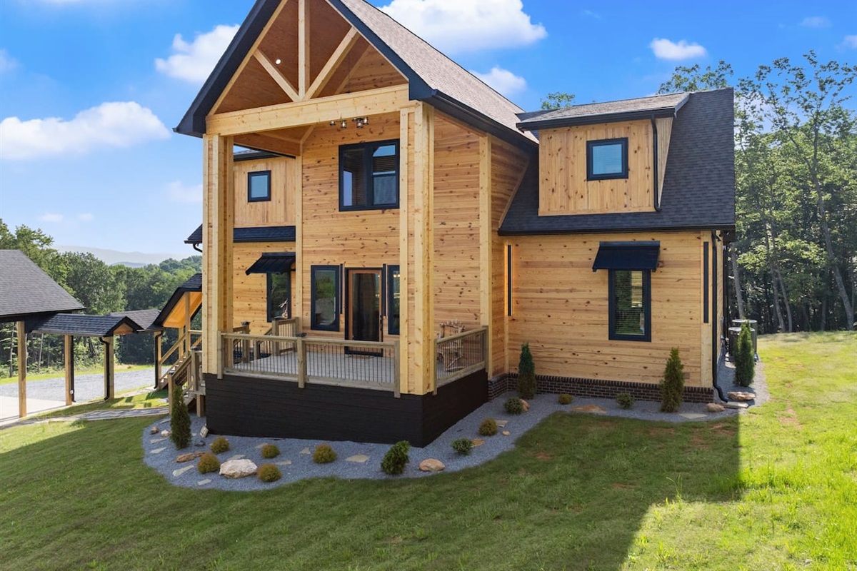 A closer look at the stunning exterior showcases natural wood finishes, black trim, and manicured stone accents.
