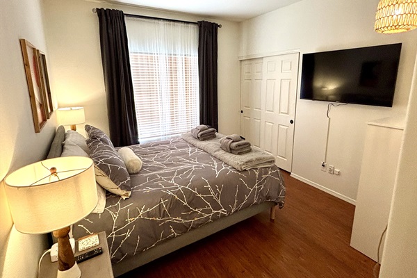 Queen bedroom downstairs with 55" smart Tv and blackout curtains