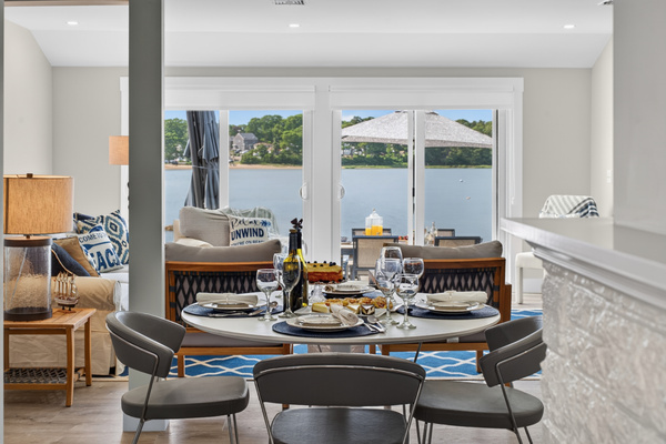 Bright open-concept living and dining area with large windows, comfortable seating, and panoramic waterfront scenery.