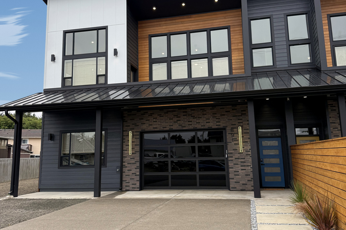 Striking modern exterior with a designer glass garage door. Side A is one half of a brand-new 2026 duplex — rent this side alone, or book both sides and open the upstairs adjoining door for up to 20 guests.