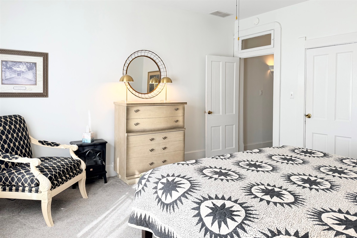 Cozy electric fireplace, vintage dresser with mirror, and a cozy sitting chair — a calm, beautifully layered corner designed for comfort and ease.