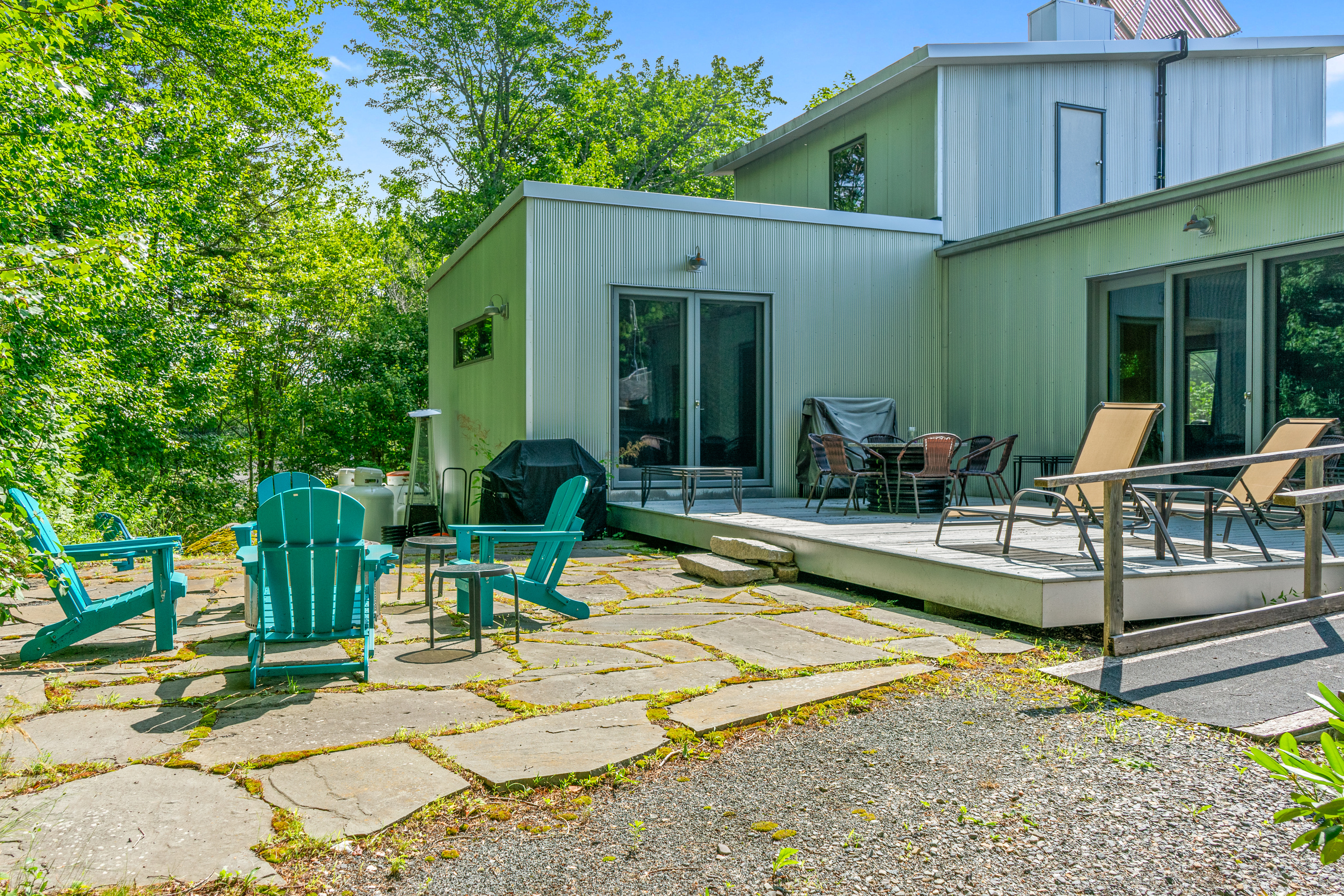 View from the natural granite yard and Solo Stove fire pit looking back at the 33ft deck. This outdoor oasis borders Acadia National Park, offering a seamless transition from the main level lounge to starlit nights by the fire.