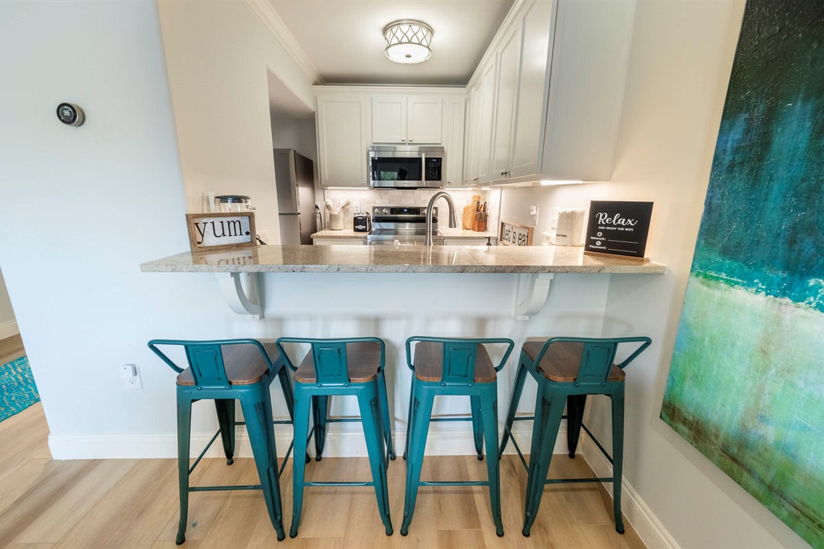 Stylish kitchen vibes: Teal stools, cozy ambiance, and modern granite design.