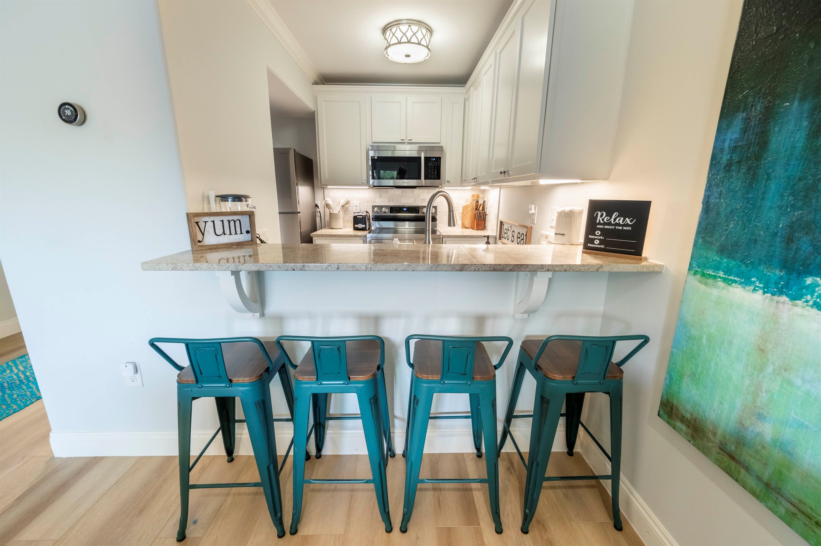 Stylish kitchen vibes: Teal stools, cozy ambiance, and modern granite design.