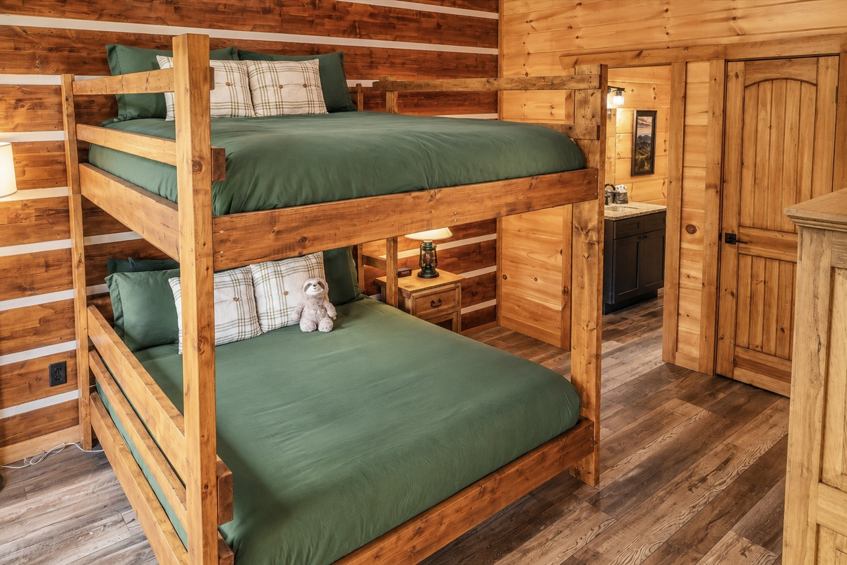Oversized log bunks dressed in forest green turn bedtime into a camp adventure.