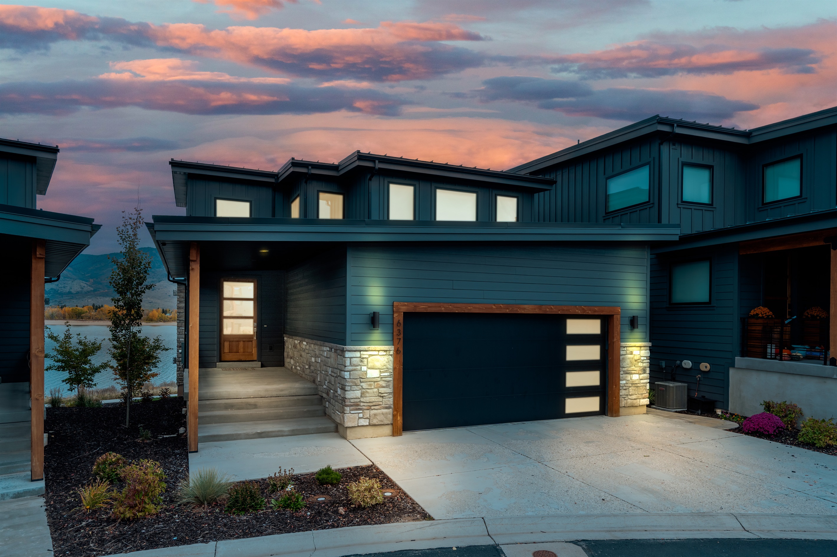 Striking architectural design with illuminated entry and two-car garage.