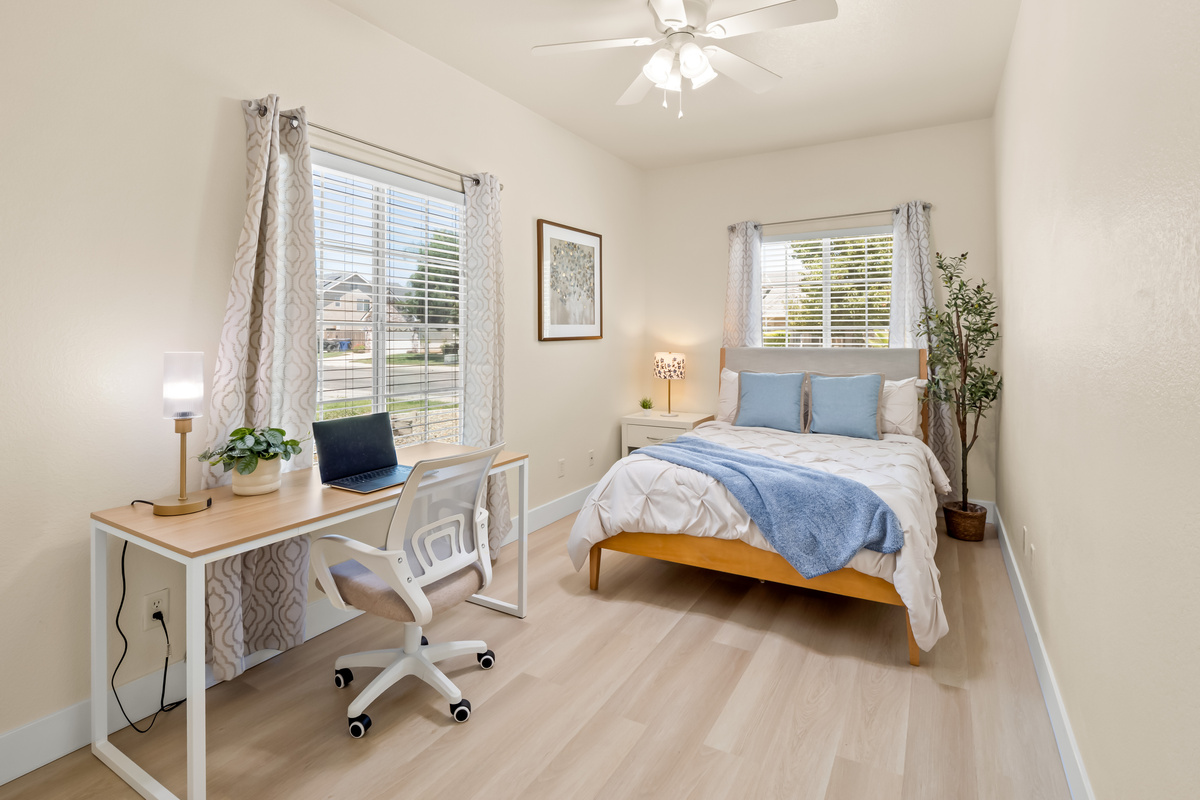 This bright and inviting bedroom offers a comfortable bed, abundant natural light, and a dedicated workspace, making it the perfect retreat for both relaxation and productivity during your stay.