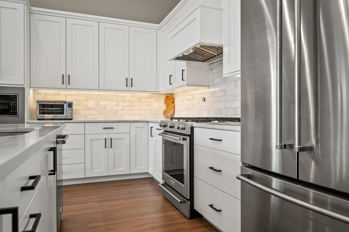 ourmet kitchen with quartz counters, island seating, gas range, and ample refrigeration.