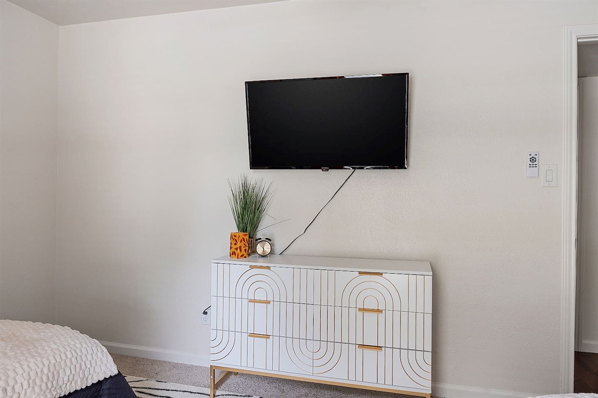 Relax and unwind in this room with a stylish dresser and a wall-mounted TV. The decor adds a modern touch to the space.