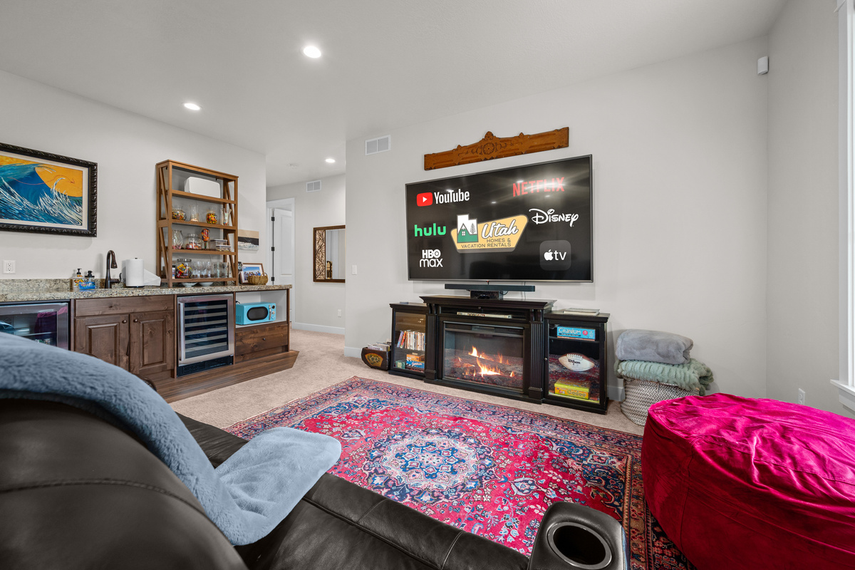 Entertainment for Everyone – Gather in the spacious lower-level media room featuring comfortable reclining seating, a large Smart TV with streaming services, and a cozy fireplace for movie nights.