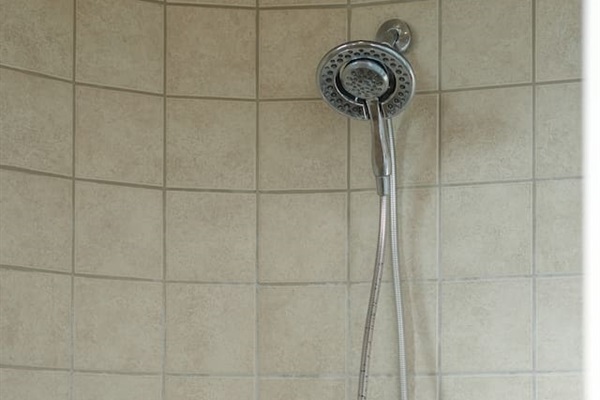 Walk-in shower featuring handheld showerhead and tiled surround.