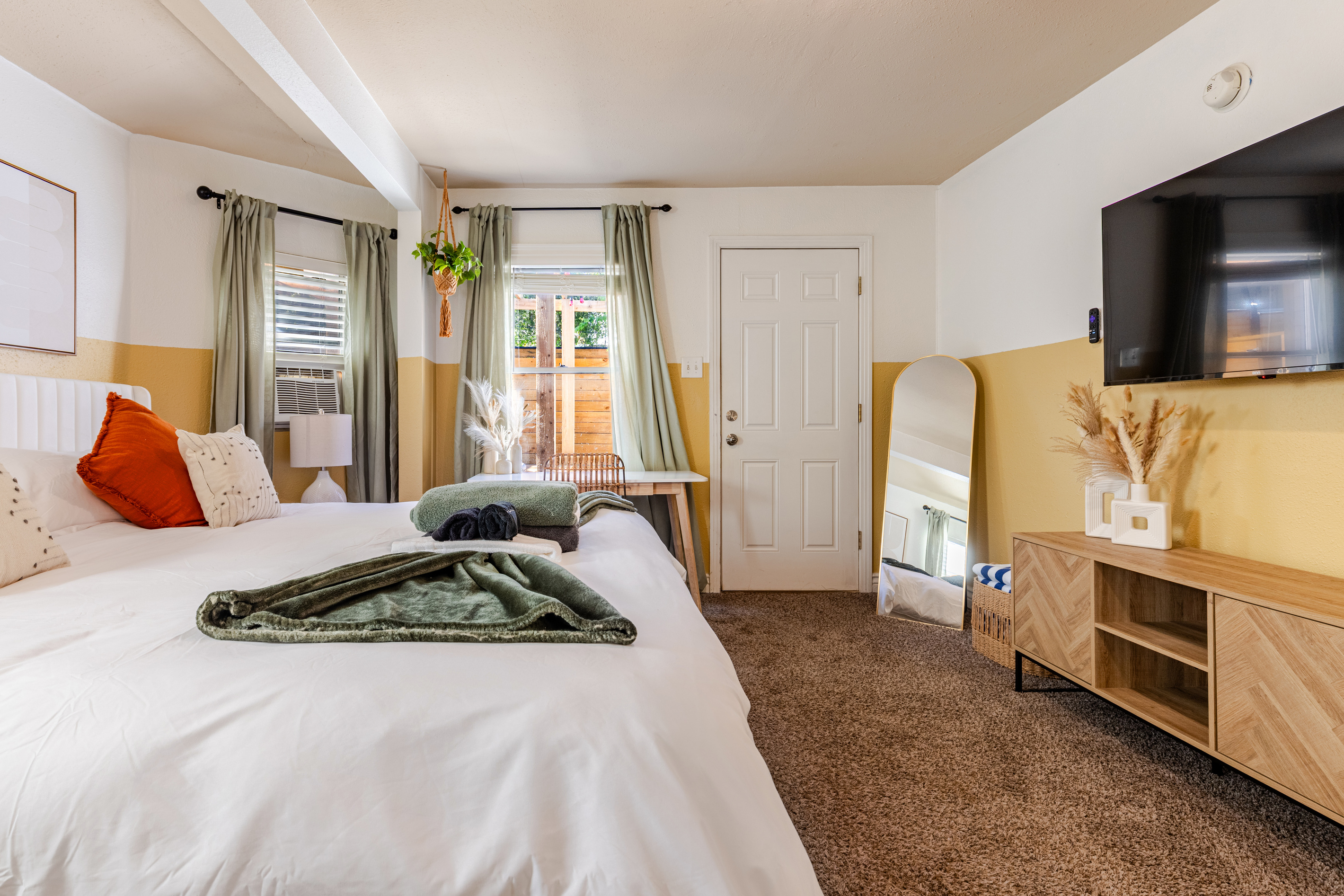 Bright room with plush bedding, modern decor, and a sunny outdoor view!