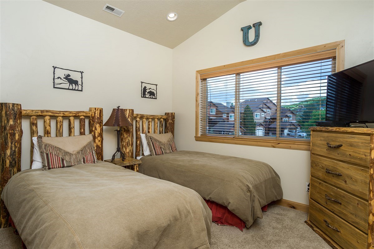 A charming twin bedroom with handcrafted log beds and warm wood tones, offering a cozy retreat perfect for guests or family stays.