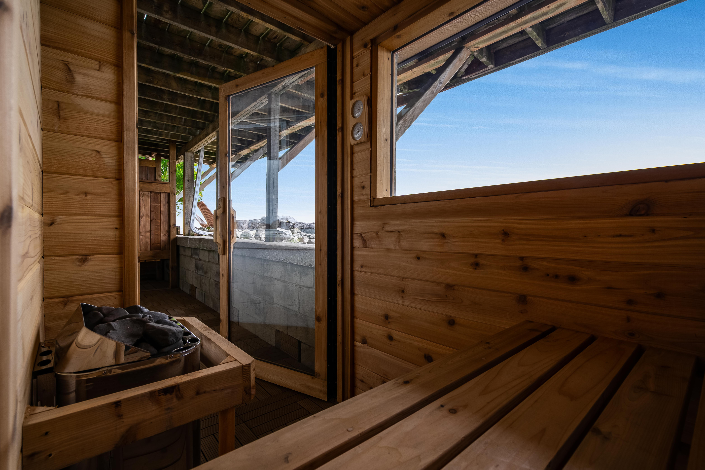 Rustic wood sauna with built-in bench seating and scenic outdoor views.