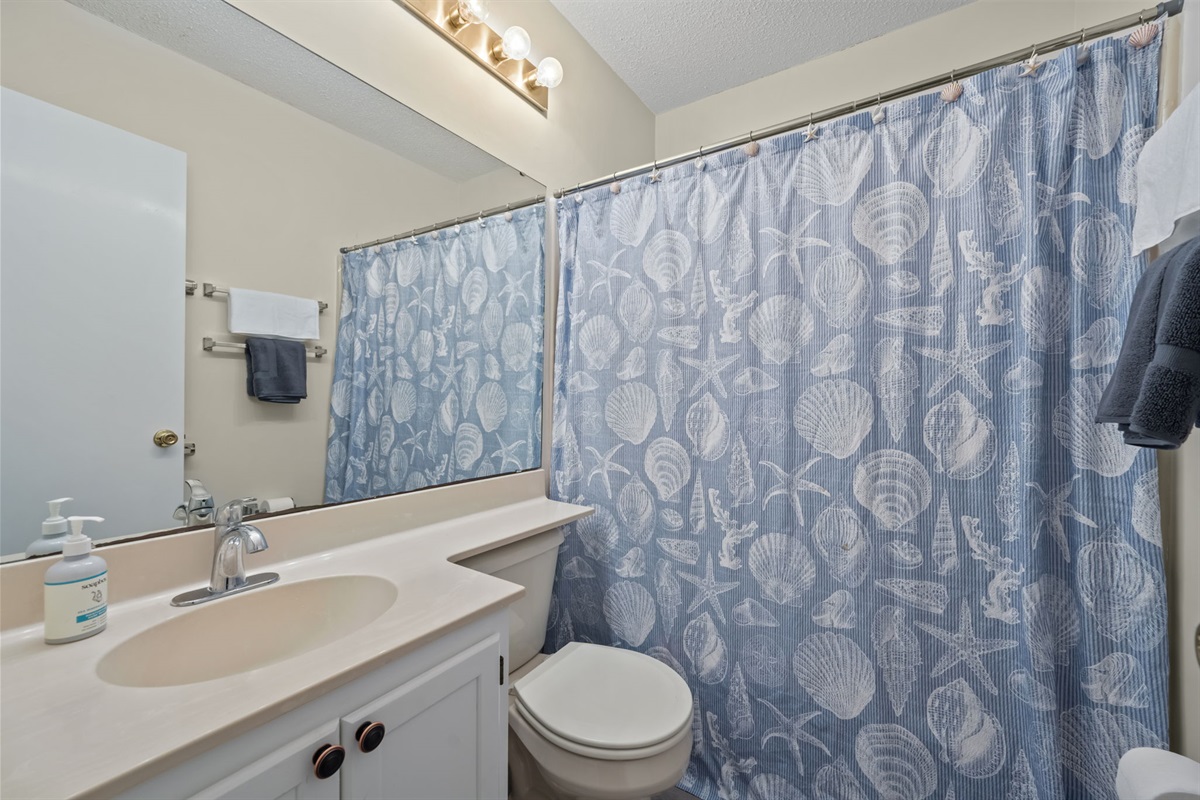 Bright, beach-themed bathroom with a tub/shower combo, fresh towels, and simple coastal touches to start and end your day comfortably
