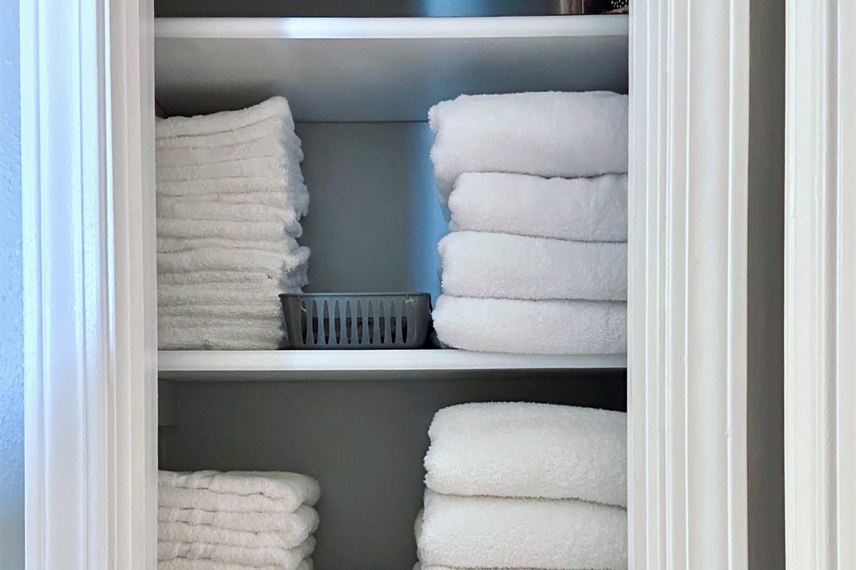 Another view of the bathroom linen closet showing neatly stacked bath towels, hand towels, washcloths, and makeup remover cloths. Fully stocked to comfortably support extended stays without perpetually doing laundry.