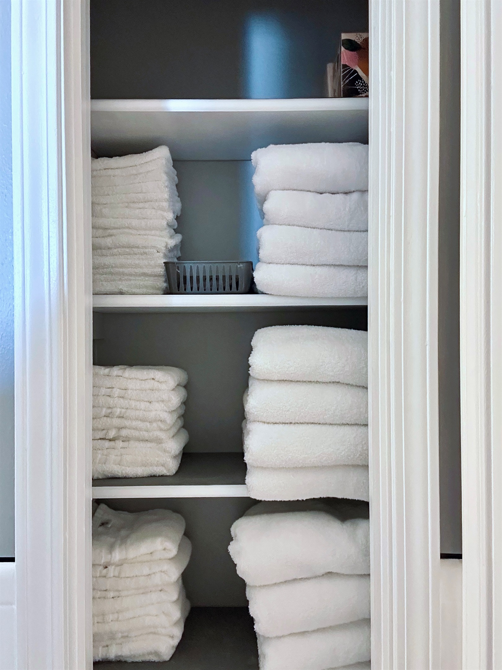Another view of the bathroom linen closet showing neatly stacked bath towels, hand towels, washcloths, and makeup remover cloths. Fully stocked to comfortably support extended stays without perpetually doing laundry.