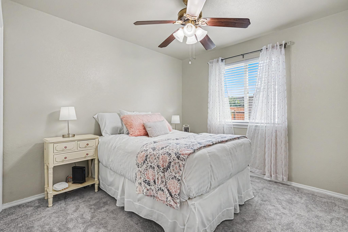 The back bedroom features a comfortable queen-size bed and a beautifully designed space with soft pink and gray accents. With its open layout and inviting atmosphere, this room provides a relaxing retreat for a comfortable night's rest.