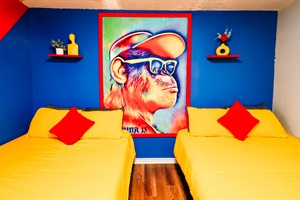 Vibrant Rest: A Cheerful Bedroom Retreat Featuring Sunny Yellow Beds, Bold Red Accents, and a Playful Monkey Artwork 🛏️🔵🐒