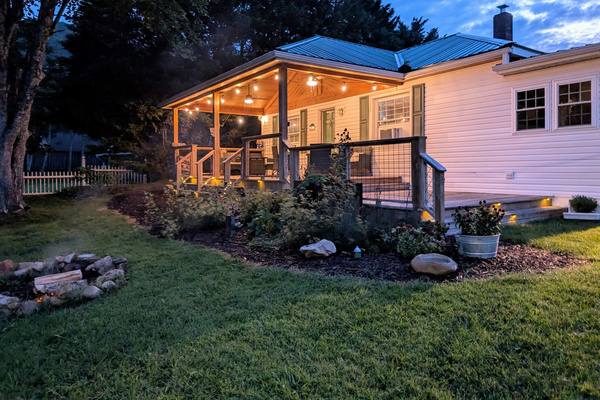 The Bailey Hot Springs — covered porch at dusk with fire in fire pit and Blue Ridge mountain views