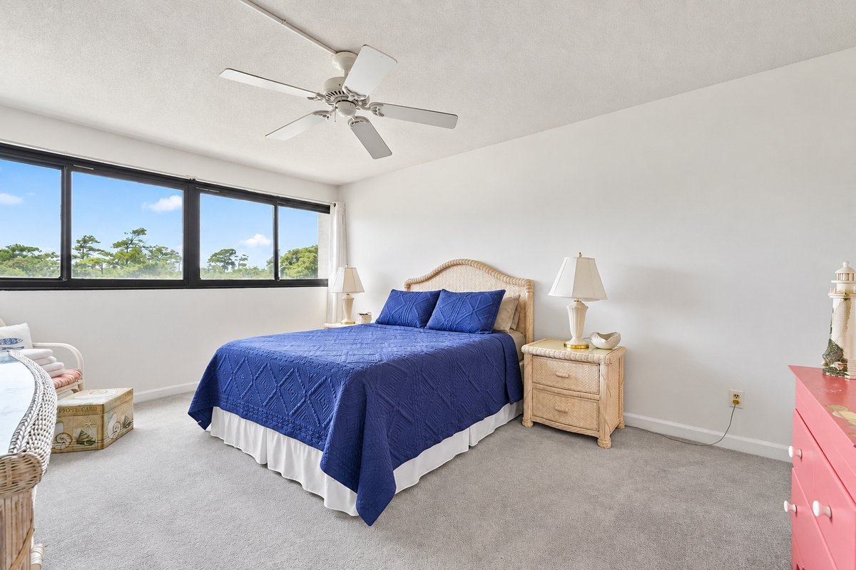 Bedroom 1 with queen bed, wide window views, ceiling fan, and extra floor space to spread out.