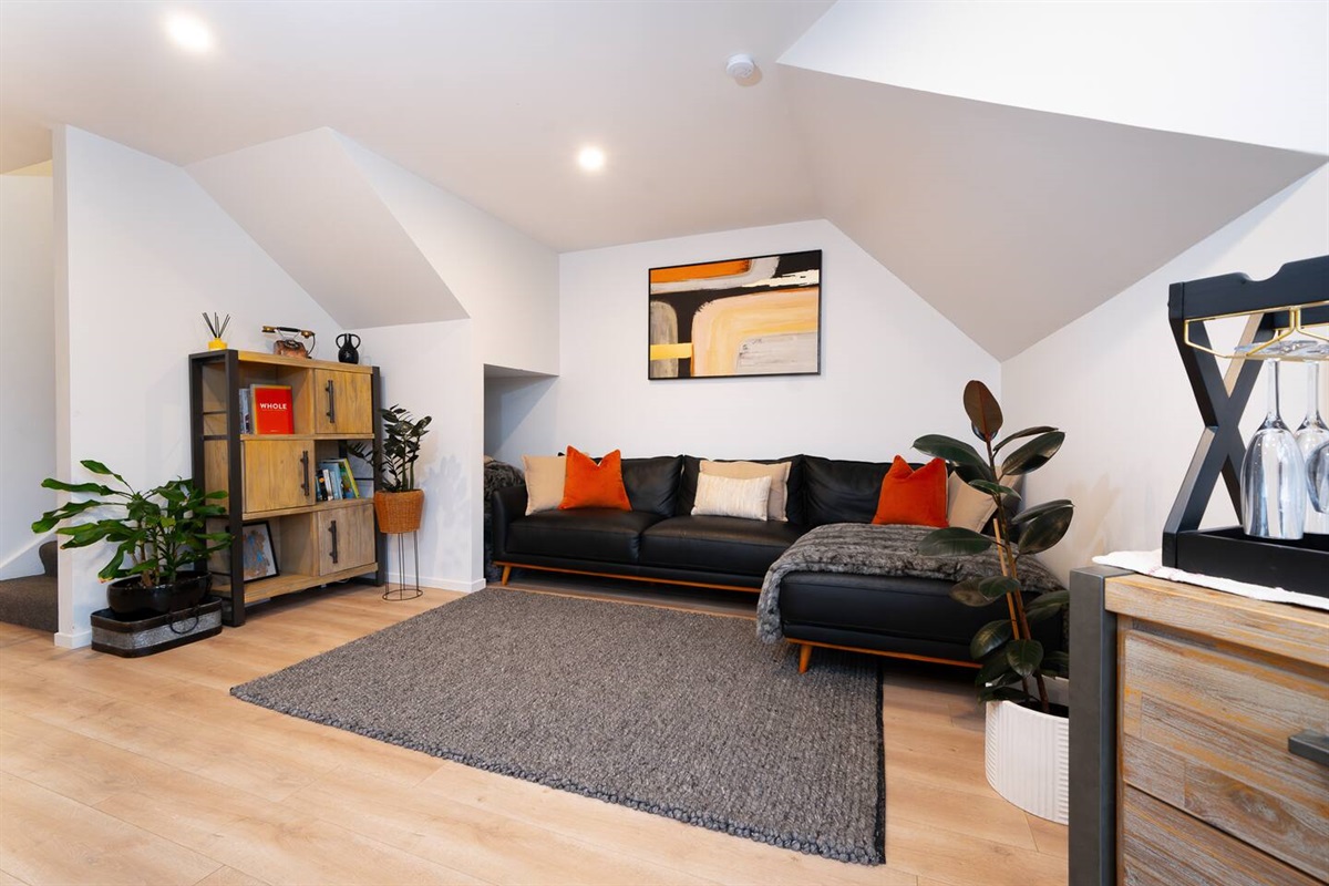 Fernhill Mountain Escape’s upstairs media lounge adds a second living space, with a large TV, deep sofa, beanbags and mountain light through the skylight.
