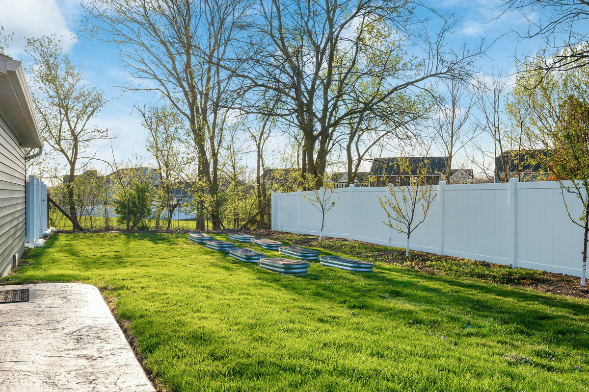 Large fenced backyard with raised garden beds and space for outdoor games.