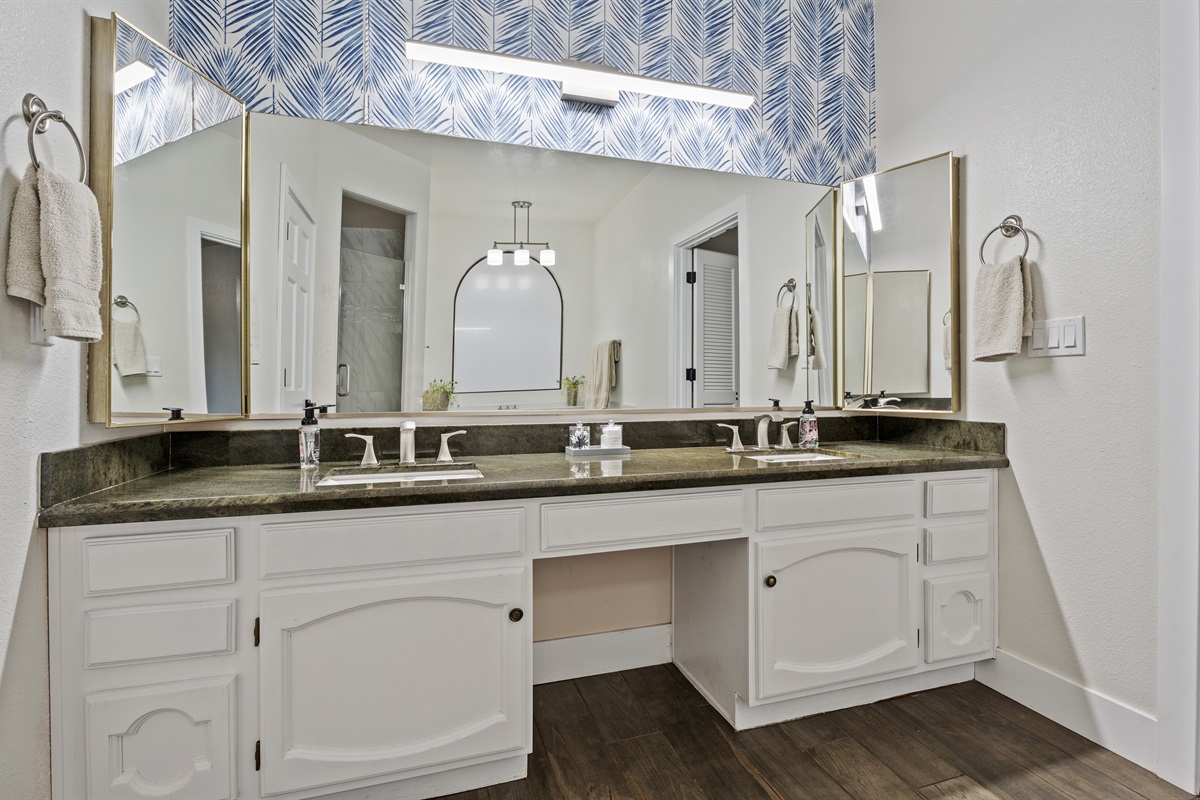 This luxurious bathroom offers double vanities, statement wallpaper, and a freestanding soaking tub made for long, peaceful escapes.