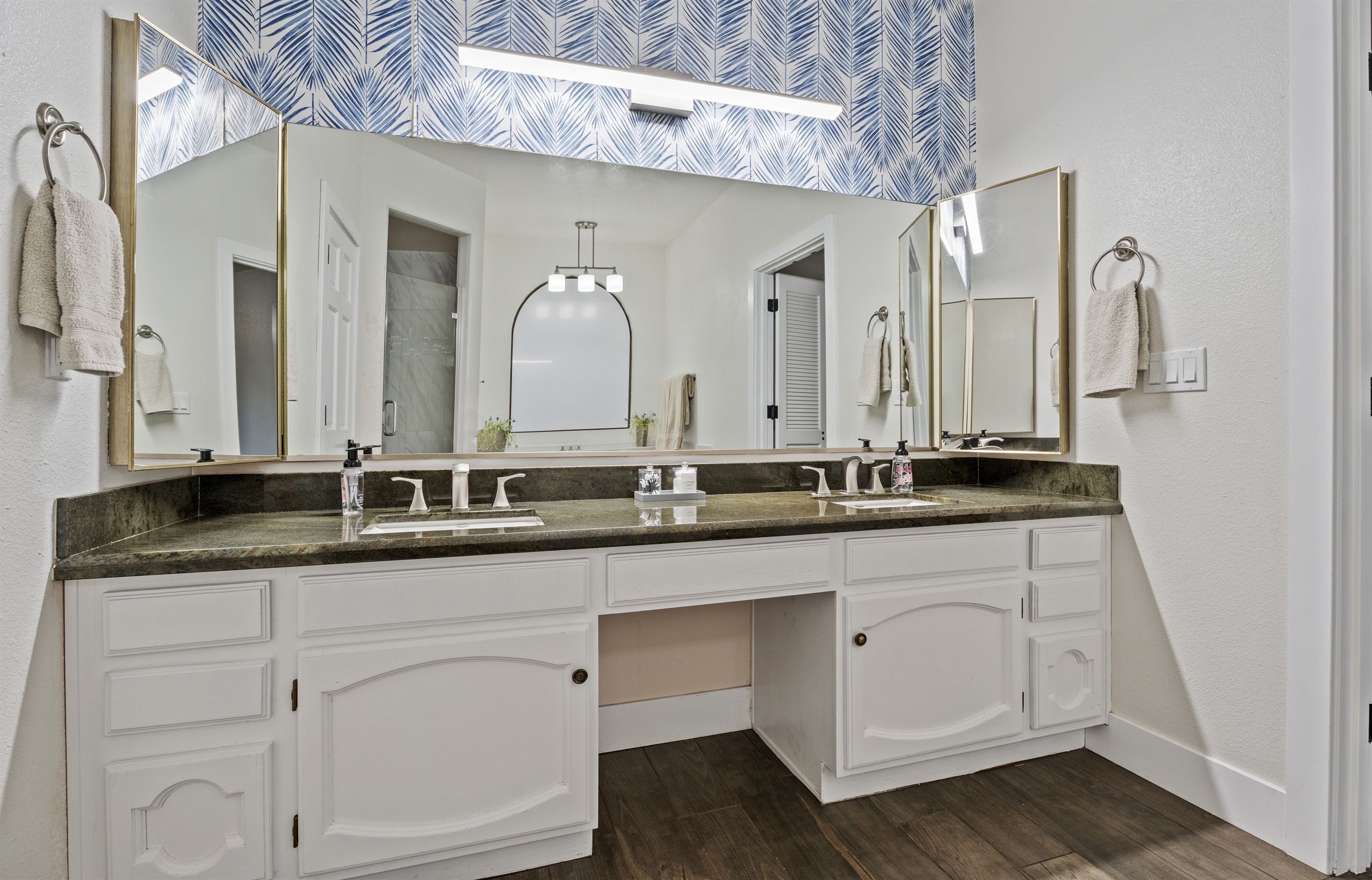 This luxurious bathroom offers double vanities, statement wallpaper, and a freestanding soaking tub made for long, peaceful escapes.