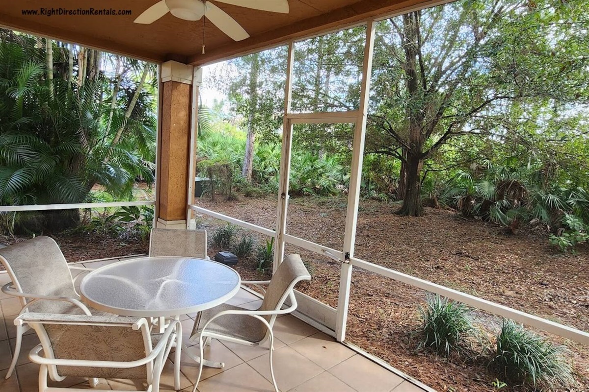 Private screened patio with outdoor seating and peaceful views of the surrounding landscaping.