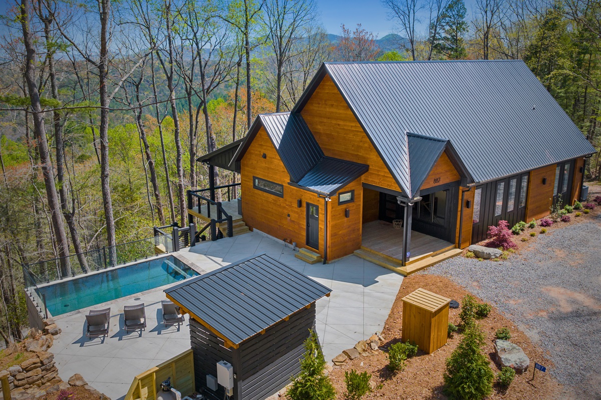 This aerial view captures the serenity of this mountain retreat where luxury meets nature. Showcasing a pristine pool set amidst the tranquil beauty of the forested landscape.