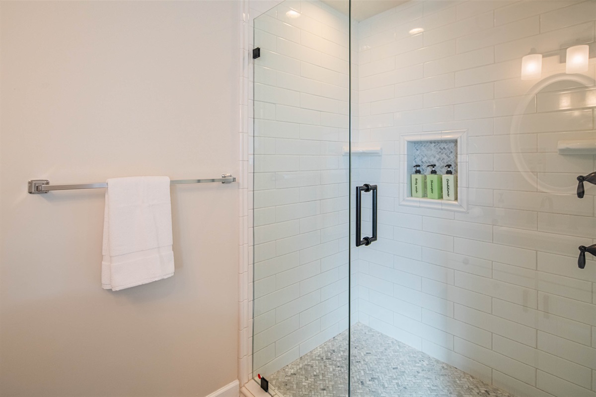 Clean, modern walk-in shower with glass enclosure and hotel-style amenities — designed for comfort and easy group use during your stay.