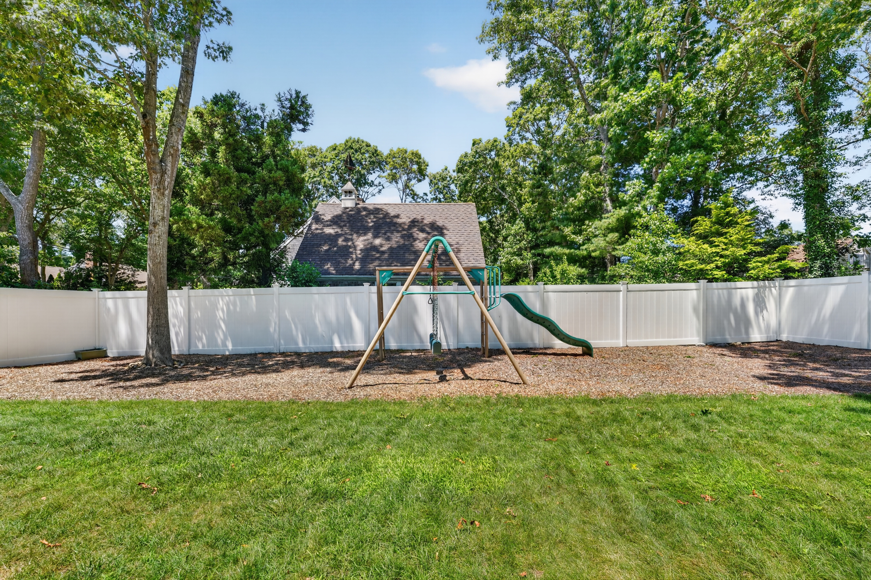 Large, fully fenced backyard with a swing set and room for everyone to play.
