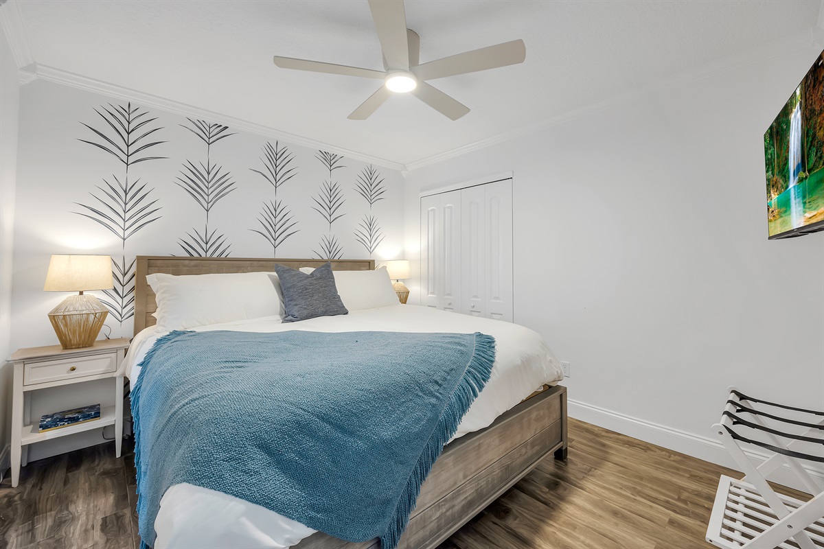 King bedroom with accent wall and soft coastal tones