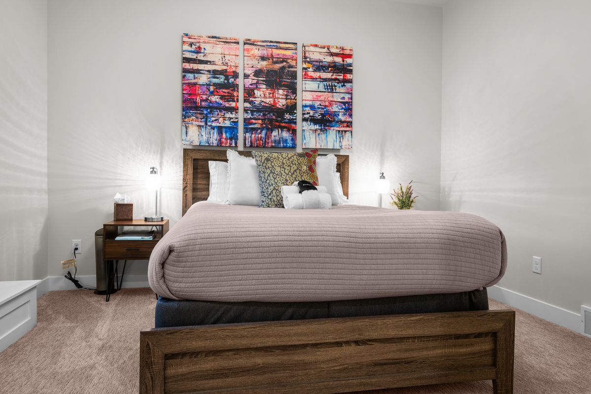 Relax in the inviting lower-level queen bedroom featuring plush bedding and modern rustic décor.