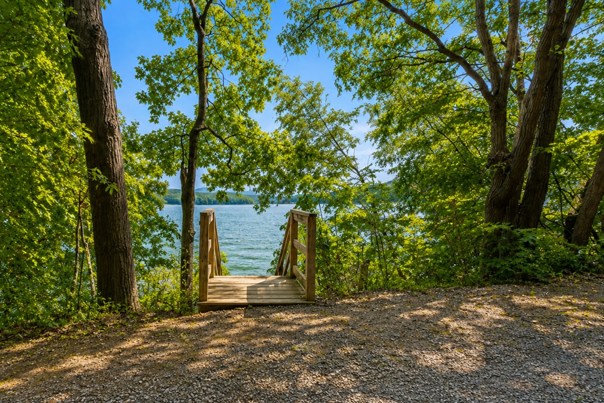 A charming woodland entrance guides you down to the sparkling lake, blending nature with relaxation.