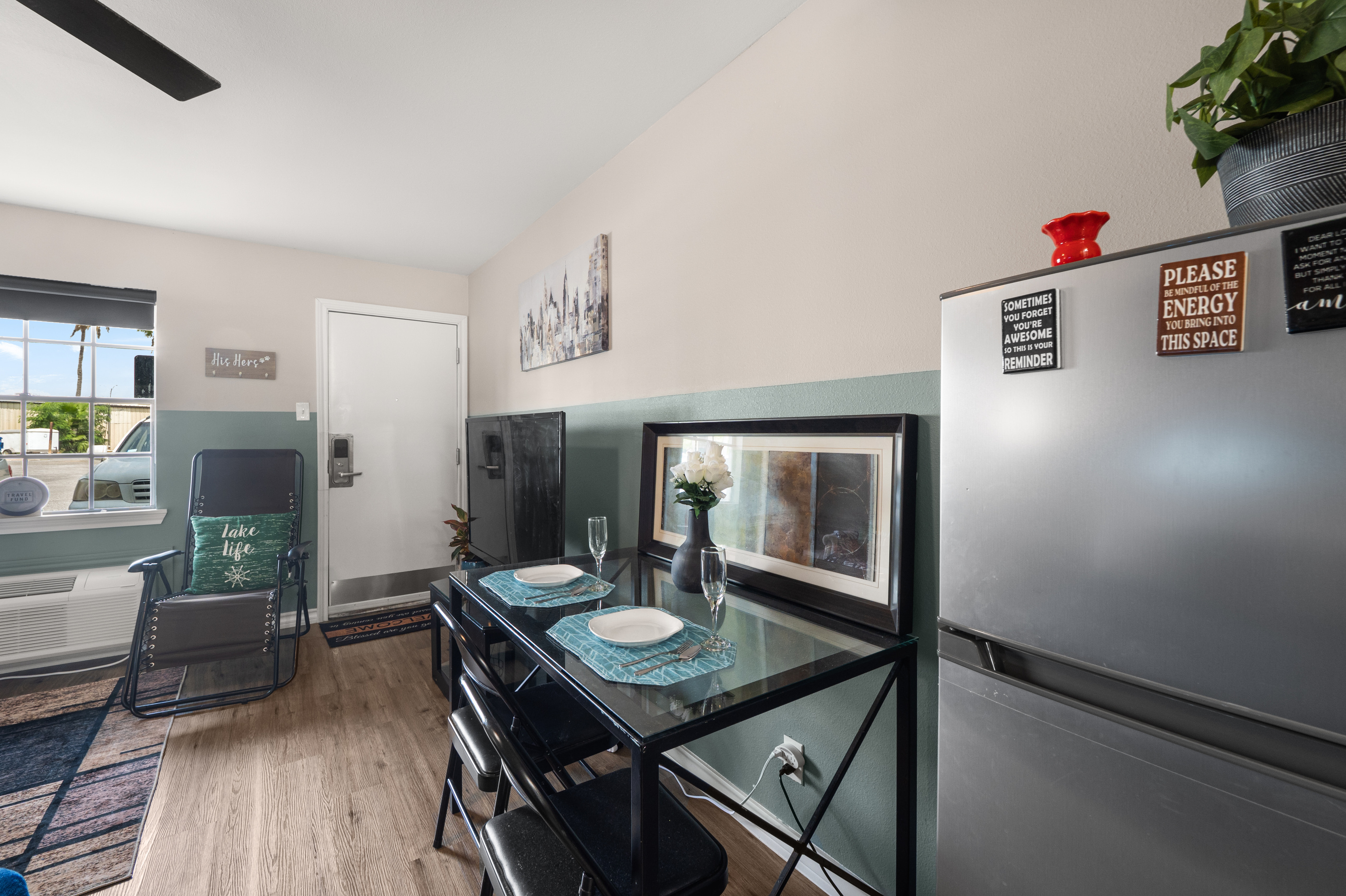 Dining corner with a small table, full-size fridge, TV, and an easy spot for meals or work.
